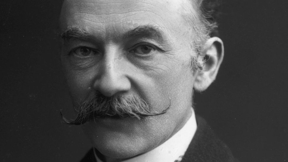 A black and white photograph of the English writer Thomas Hardy as a man in his late 40s or early 50s, sporting a  handlebar moustache.